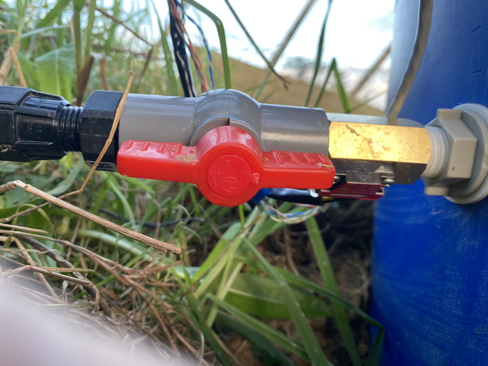 Close-up of the brass pulse water meter and red ball valve on the reservoir top-up line